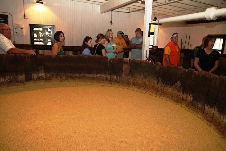 見学者は木桶発酵槽でのすぐ側で発酵液を見られる。ツアーガイドは発酵液を汲んで試飲させてくれた